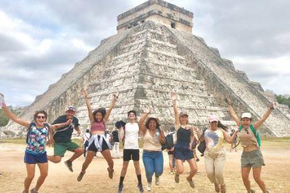 students jumping in front of Aztec pyramid